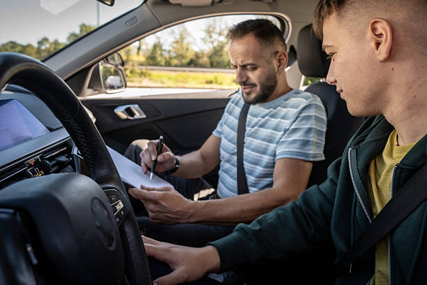 istock Driving Instructor Reviews Notes with Student in Car 2251314389