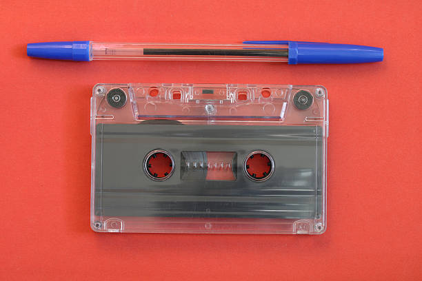 Cassette tape and blue pen on a red background featuring vintage music technology