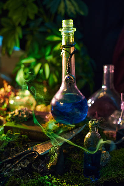 istock Several glass potion bottles filled with blue liquid sit on a wooden table. table is covered with plants and herbs under low light, creating a mysterious scene 2251319608