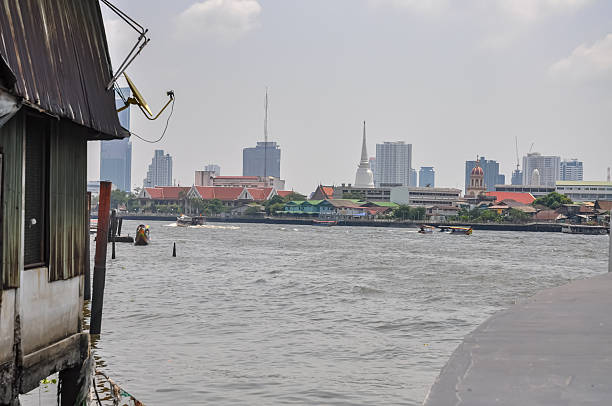 istock Dramatic Contrast in Architecture: Old Waterfront Homes and Dilapidated Buildings Against Modern Skyscrapers and Luxury Condos on the Chao Phraya River in Bangkok, Thailand 2251320143