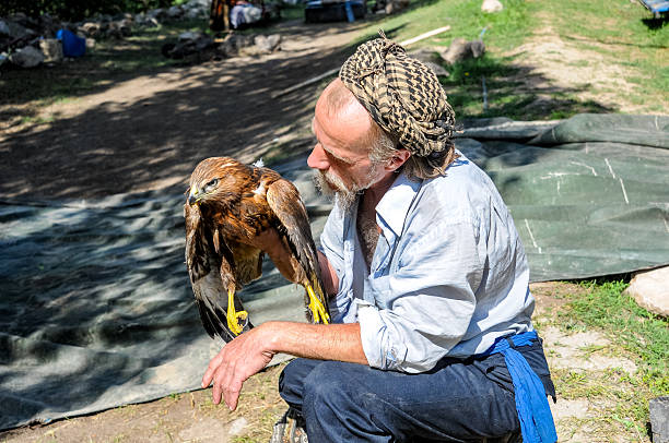 Ağrı, Türkiye - August 05, 2009: A bohemian-styled man examines a wounded hawk for treatment.