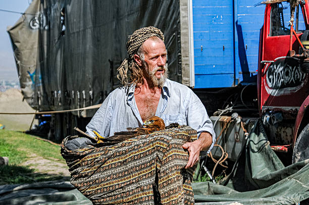 Ağrı, Türkiye - August 05, 2009: A bohemian-styled man looks after a wounded hawk for treatment.