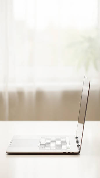 istock Minimalist side view of an open laptop on a white table in a bright room 2251320252