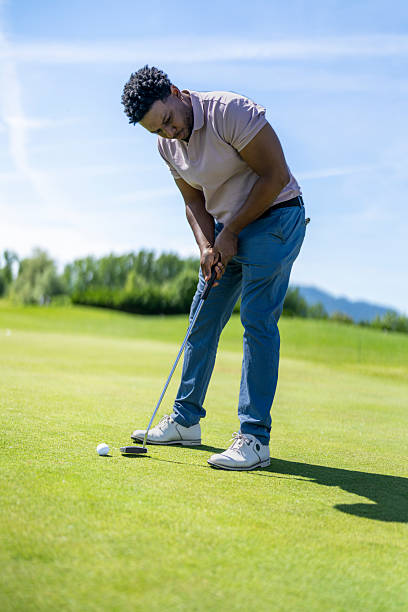 istock Young Hispanic Man Focused on Putting During Sunny Day on Golf Course Green 2251320370