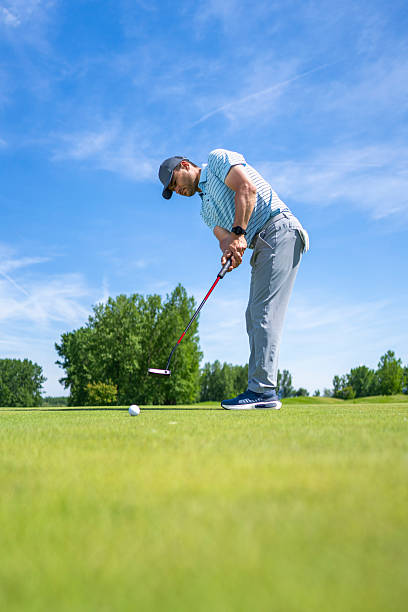 istock Determined Caucasian Man Focused on Putting Under Clear Sky on Golf Course 2251320474