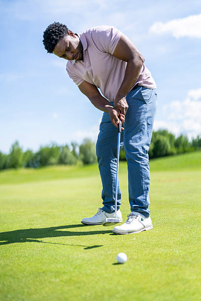 istock Young Hispanic Male Golfer Putting with Focus on Sunlit Green 2251320505
