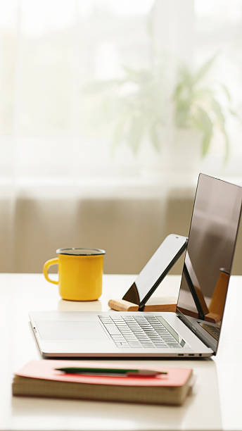 istock Modern workspace with open laptop, yellow coffee mug, phone and notebook on desk 2251320861