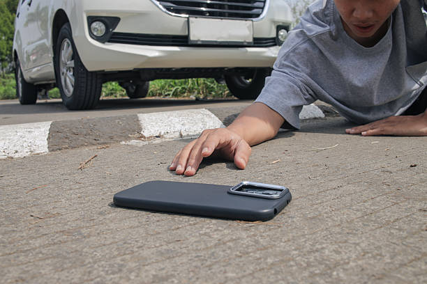 istock Distressed Man Reaching for Dropped Phone Near Car 2251323401