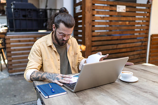 istock Focused man working remotely outdoors with laptop and coffee 2251328405