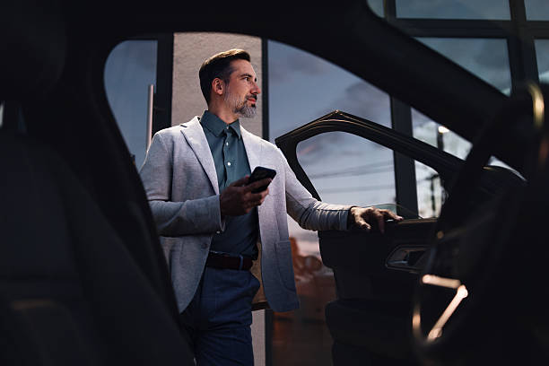 istock Professional Businessman Checks Phone While Entering Office Car at Evening Work Scene 2251332221