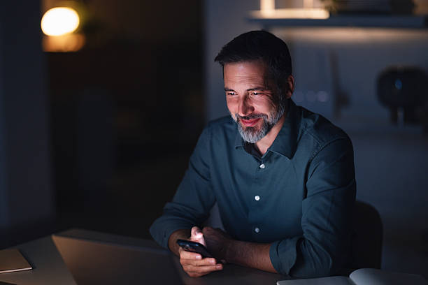 istock Businessman Working Late at Night in Modern Office, Smiling While Using Phone 2251332285