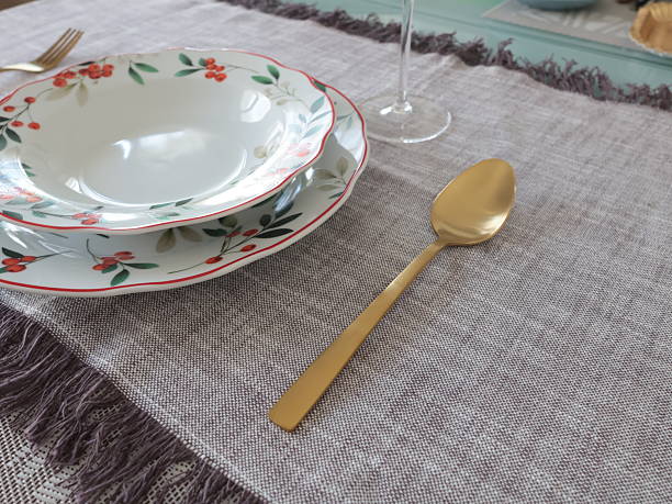 istock Golden yellow spoon placed next to soup and dinner plates with floral pattern on table. 2251332774