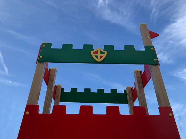 The playground is often covered in soft mulch, rubber mats, or grass for safety, and the area is surrounded by benches or picnic tables where parents and caregivers can sit and watch
