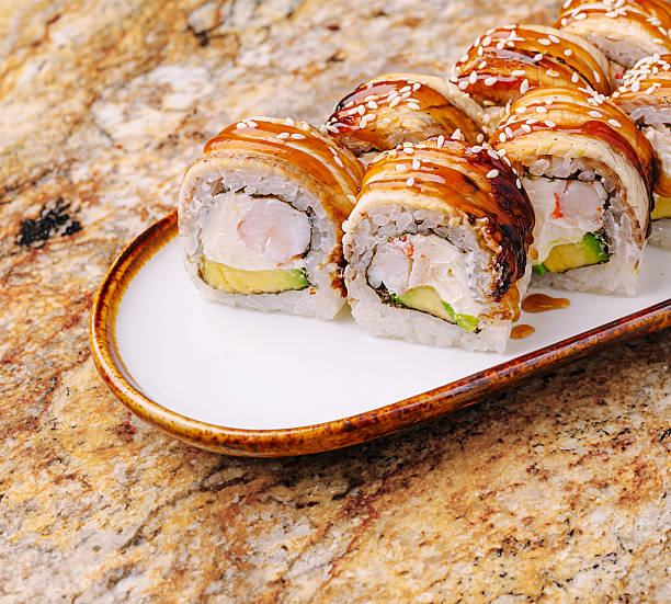 istock Sushi rolls served on a white plate with a golden rim on a marble table 2251337041