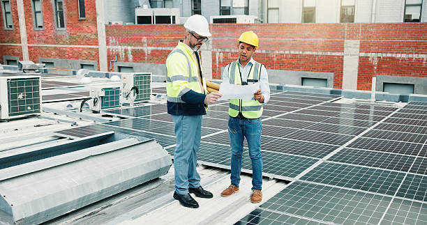 istock Solar panels, team or engineer on rooftop with blueprint, construction or maintenance planning. Collaboration, photovoltaic grid or people check for electricity production, clean energy or renovation 2251340492