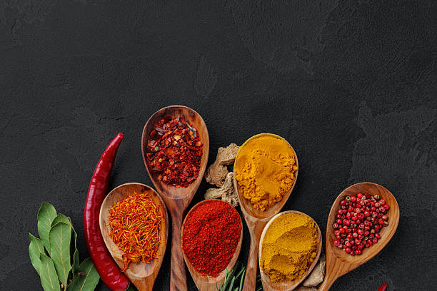 istock Wooden spoons with various spices on black background 2251341402