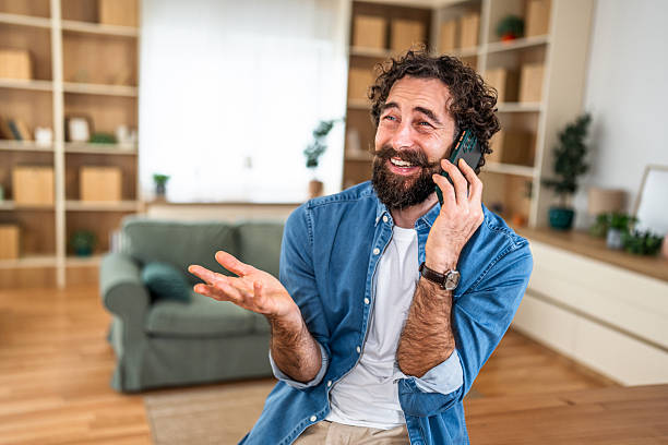 istock Bearded man talking on smartphone at home 2251341422