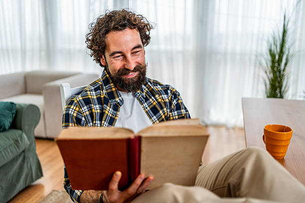 istock Happy man relaxing at home reading book 2251341862