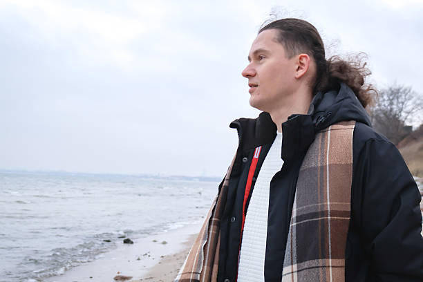 istock Strong, confident man standing on a cold seaside beach, looking toward the horizon. 2251341982