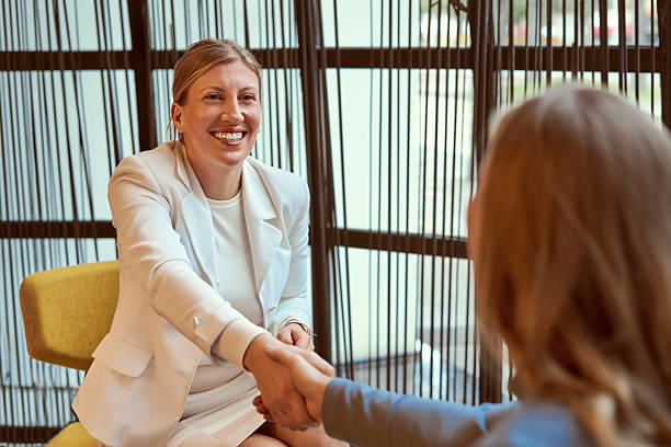 istock Business Meeting: Two Women Shake Hands And Smile In Modern Office Setting 2251344266
