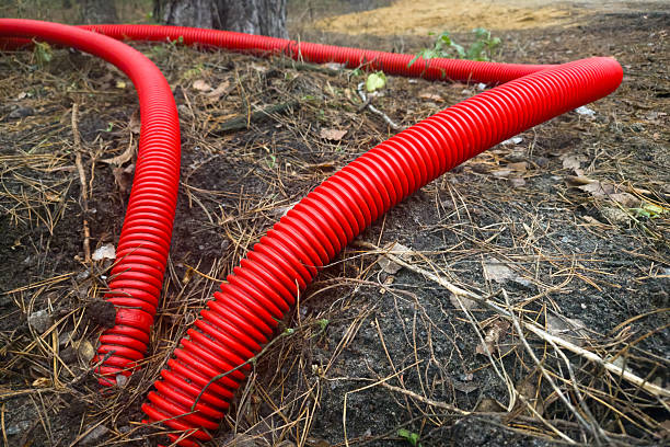 istock Red corrugated electrical conduit for cable protection on forest ground. Utility infrastructure, outdoor installation, cable management. Real photo. 2251345382