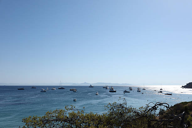 Athens, Greece - July 6, 2025. A scenic coastal view with multiple yachts and boats anchored in the calm blue sea, with mountain silhouettes in the background and a clear cloudless sky. Captured on a bright summer day in the Greek islands, perfect for travel and lifestyle concepts.