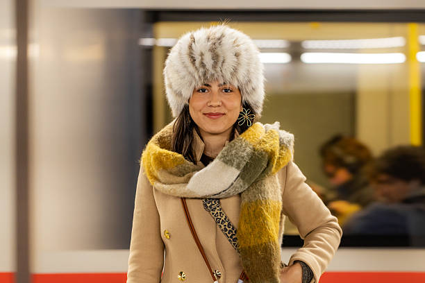 Female model wearing warm winter attire, including a fur hat, smiling softly at the camera.
