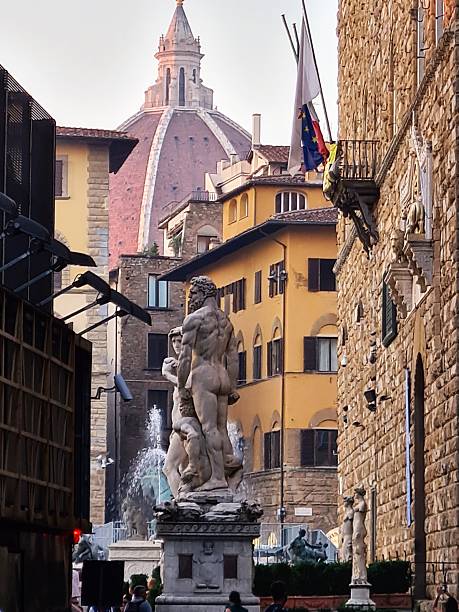In the heart of Florence, the striking marble statue of “The Rape of the Sabine Women” stands as a powerful depiction of human emotion and classical artistry. Positioned in Piazza della Signoria, the statue captures the intense moment of struggle between two figures. A man forcefully lifts a woman in an emotional display, with the detail of their intertwined bodies and the tension between them highlighting the sculptor’s skill. This statue, created by Giambologna, is surrounded by the architectural splendor of the square, contrasting history with the modern city life in the background. The cloudy sky above adds an atmospheric touch, enhancing the emotional depth of the scene.