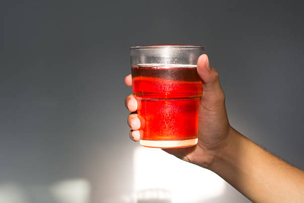 istock Glowing Glass of Tea Held in Hand Against Grey Background 2251347809