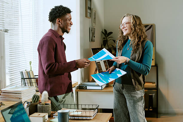 istock Young Caucasian Woman and Young Black Man Exchanging Documents in Office 2251350913