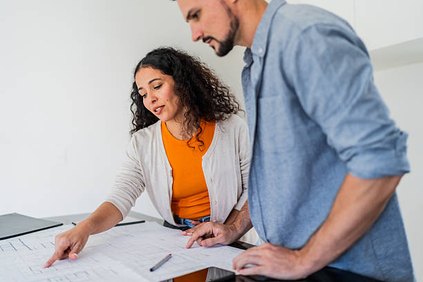 istock Couple talking and looking blueprint at new house 2251351149