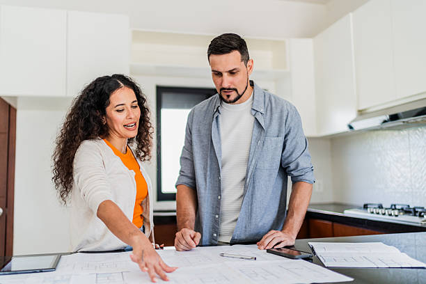 istock Couple talking and looking blueprint at new house 2251351155