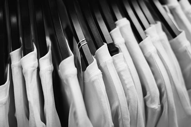 Minimalist row of white t-shirts hanging on black hangers, clean fashion display and organized texture.