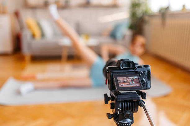 istock Young Woman Filming A Tutorial On Camera While Doing Side Lying Leg Raise At Home 2251354956