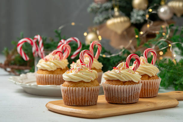 Christmas festive cupcake with creamy frosting and candy cane on light background