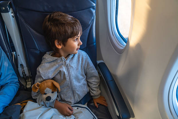 istock Young boy looking out of airplane window during flight 2251364670
