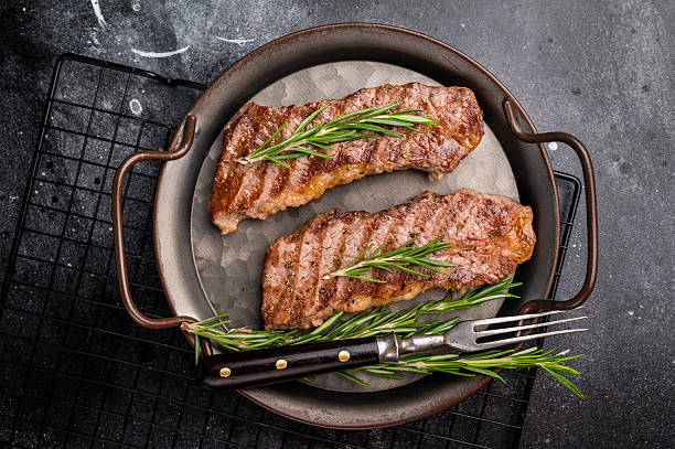 istock BBQ roast marbled beef Steak, beef meat on tray with herbs. black background. top view 2251365231