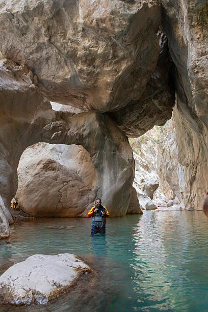 Goynuk, Turkey - October 6, 2025: Photographer waiting travelers rafting through turquoise water and cliffs in Goynuk canyon.
