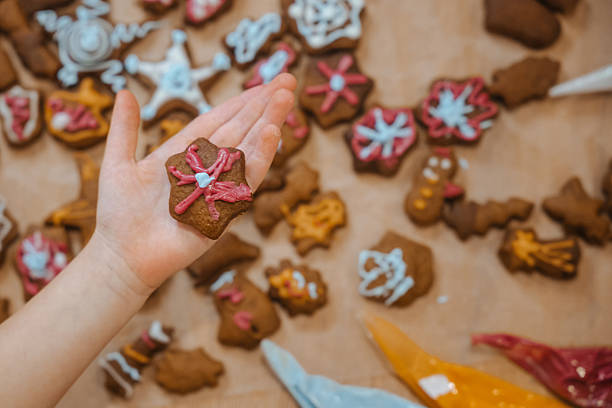 istock Child holds decorated cookie with other cookies spread out on table during baking activity 2251373308