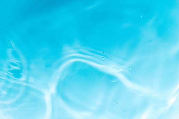 Close-up view of rippling blue water with sunlight reflections on a swimming pool surface, creating a calming abstract pattern.