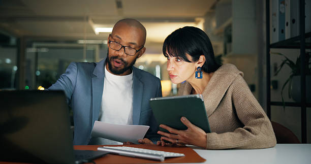 istock Laptop, team and business people in office for report, collaboration and feedback. Tech, drafting proposal and research with discussion for proofreading, review and editing publication at night 2251378618