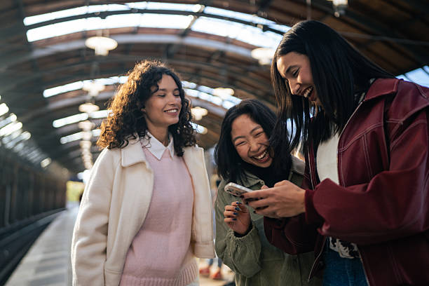 istock Three Friends Laughing While Looking at a Smartphone at the Train Station 2251383095