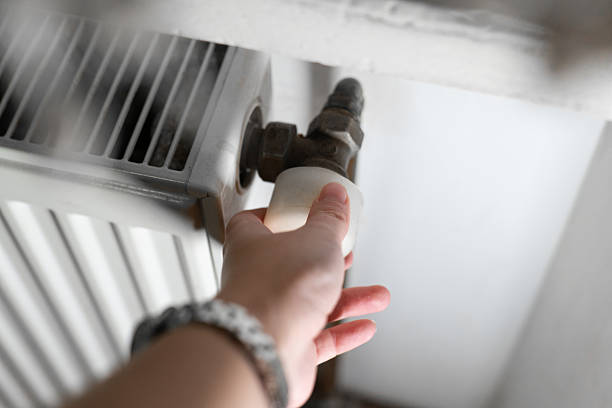 istock A hand adjusting a radiator valve in a home interior. The image represents heating control, energy saving, and household maintenance. 2251384127