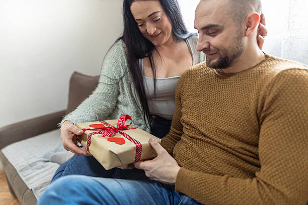 istock Woman giving her partner a wrapped gift at home. 2251384331
