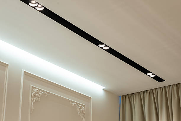 istock Suspended ceiling with halogen spots lamps and drywall construction in empty room in apartment or house. Stretch ceiling white and complex shape. 2251384599