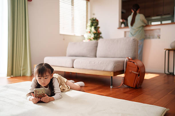 istock Young child using smartphone while mother is at home in background 2251386627