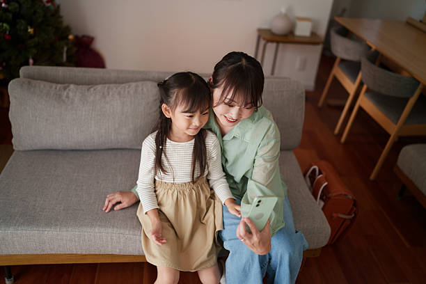 istock Mother and daughter sitting together using a smartphone at home 2251386817