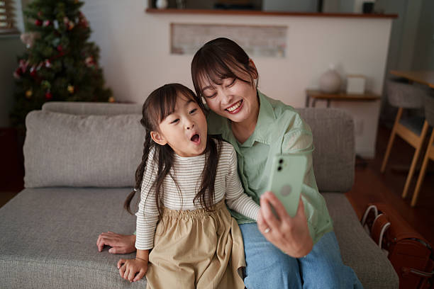 istock Mother and daughter sitting together using a smartphone at home 2251386822