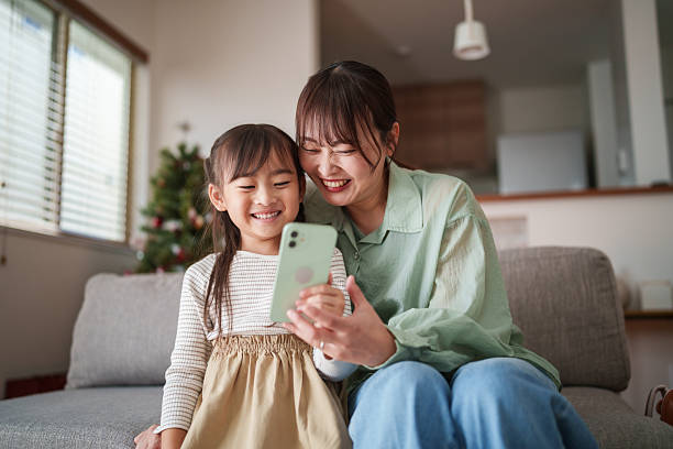 istock Mother and daughter sitting together using a smartphone at home 2251386937