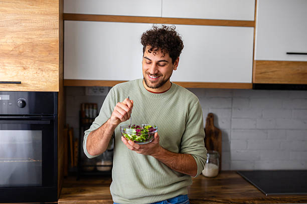 istock Man Enjoying a Bowl of Salad in Modern Kitchen 2251394498